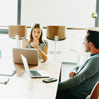 A man and woman with laptops sitting in a meeting